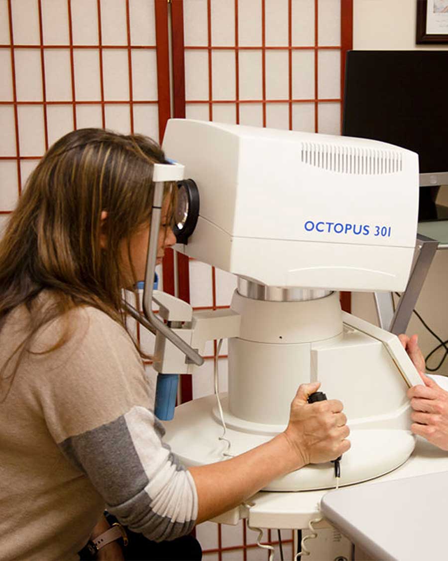 An optometrist performs an eye exam on a young boy in a clinical setting.